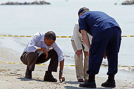 Obama recoge una bola de alquitrán en una playa de Luisiana. | AFP
