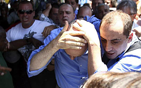 José Serra se lleva las manos a la cabeza tras ser agredido. | Reuters