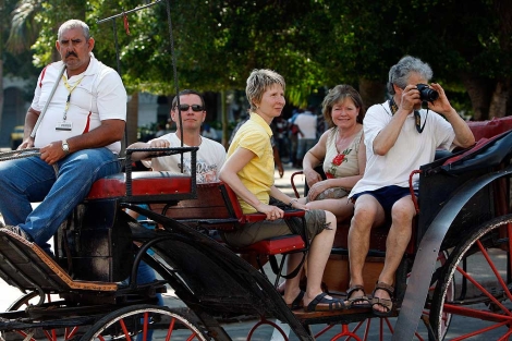 Un grupo de turistas pasea en una carro tirado por caballos en las calles de La Habana. | Efe