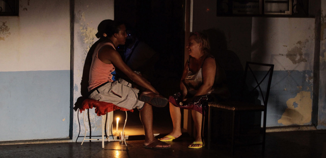 Dos personas sentadas a la puerta de una casa en La Habana durante el apagón. | Reuters