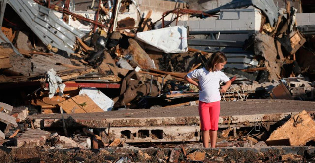 Una niña mira su casa destrozada por el tornado. | Afp