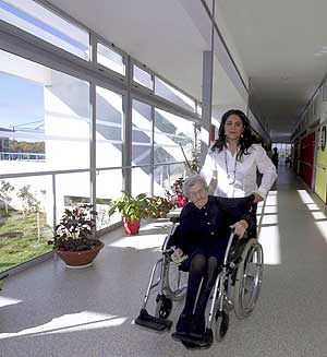 Una mujer pasea a una anciana por el pasillo de una residencia. (Foto: Mariam A. Montesinos)