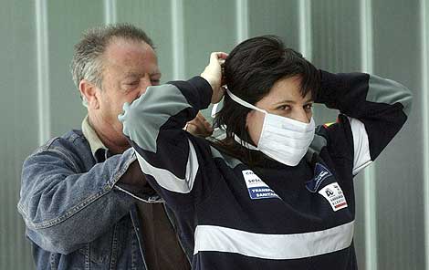 Dos operarios de ambulancia se colocan las mascarillas. | Efe