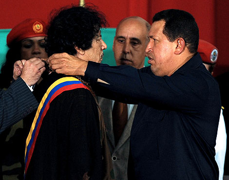 Chávez entrega un obsequio al líder libio. | Afp
