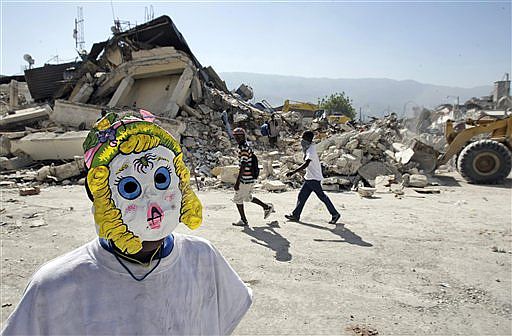 Un niño se oculta con una máscara de carnaval en las ruinas de Puerto Príncipe. | AP