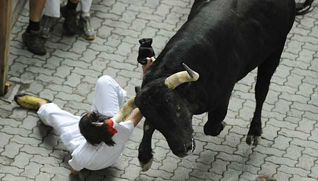 Un joven ha sido prendido por la camiseta y arrastrado por el toro en el callejón en los Sanfermines. | Afp