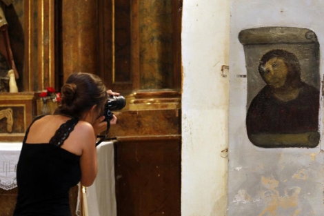 Una mujer fotografía la versión 'restaurada' del Ecce Homo. | AFP