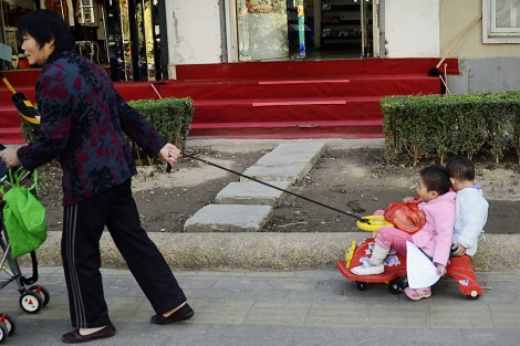 Una mujer arrastra un carrito con dos niños en Pekín. | Afp