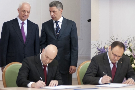 El primer ministro de Ucrania, Mykola Azarov (de pie a la izq.) mientras el falso representante, Jordi Sardà Bonvehi (sentado, izq.), firmaba el acuerdo. | Reuters El primer ministro de Ucrania, Mykola Azarov (de pie a la izq.) mientras el falso representante, Jordi Sardà Bonvehi (sentado, izq.), firmaba el acuerdo. | Reuters