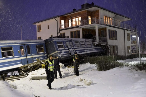 Policías suecos junto al tren empotrado en un bloque de viviendas. | Reuters