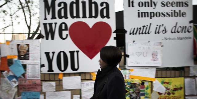 Una mujer pasa delante de la pared en la que se han colgado los mensajes de ánimo a Mandela. | Afp