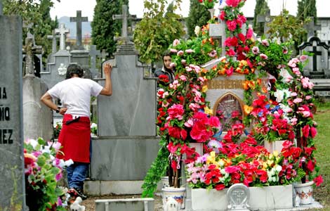 Dos jóvenes visitan la tumba de un familiar en el cementerio de Derio (Vizcaya). | Mitxi