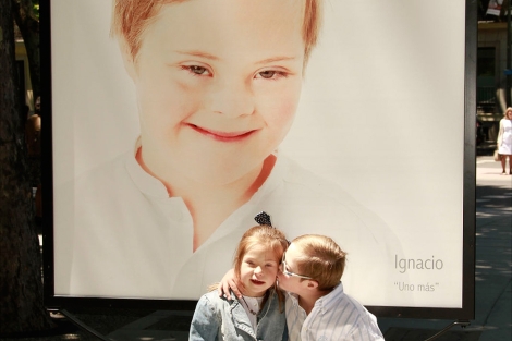 Dos niños con síndrome de Down se besan en una exposición.| EM