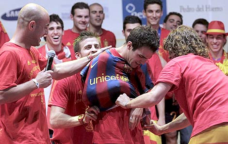 Puyol y Piqué ponen la camiseta del Barça a Fábregas, durante la celebración. | Efe